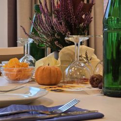 Ein festlich gedeckter Tisch mit Kürbis, Heidekraut und herbstlichen Blättern sorgt für eine gemütliche Atmosphäre.