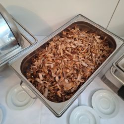 Ein Tablett mit frisch geschnittenem, gebratenem Fleisch steht auf einem Buffet, bereit zum Servieren.