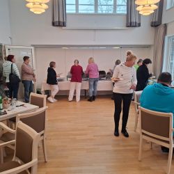 Menschen stehen in einer Kantine an einem Buffet an, während andere an Tischen sitzen und essen.