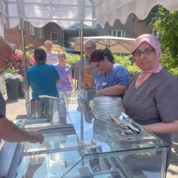 Eiscreme wird an einem sonnigen Tag von Mitarbeitenden an einem Stand serviert, während Gäste warten. | © Name