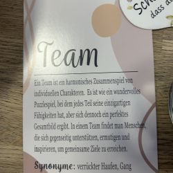 Eine Karte mit dem Titel "Team" beschreibt harmonische Zusammenarbeit, daneben ein Willkommensschild mit "Schön, dass du da bist".