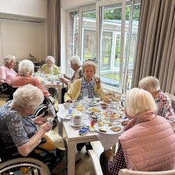 Ältere Frauen genießen ein gemütliches Frühstück in einem sonnendurchfluteten Raum voller Fröhlichkeit und Gemeinschaft.