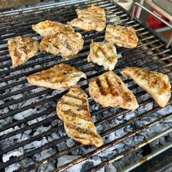 Mehrere Stücke gegrilltes Fleisch brutzeln auf einem Holzkohlegrill und versprühen einen köstlichen Grillduft in der Luft.