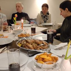 Eine Gruppe von Menschen sitzt an einem Tisch und genießt in gemütlicher Atmosphäre Pommes und Getränke.