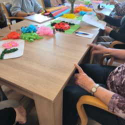Eine Gruppe von Frauen bastelt mit buntem Papier an einem Tisch in einem kreativen Workshop. | © Name