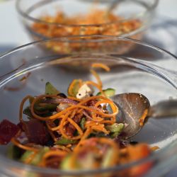 In einer Glasschüssel wird ein frischer Salat mit Karotten, Gurken und Tomaten präsentiert, bereit zum Genießen.