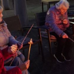 Ältere Frauen rösten Marshmallows über einem gemütlichen Lagerfeuer im Freien und genießen die entspannte Atmosphäre.