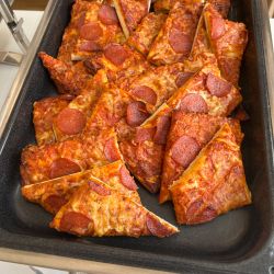 Eine große Menge geschnittener Pepperoni-Pizza liegt auf einem Tablett und ist bereit für eine Party oder ein Buffet.