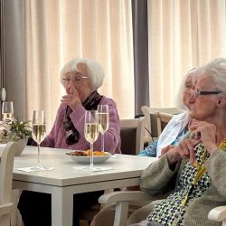 Ältere Frauen genießen ein geselliges Treffen mit Sekt und kleinen Snacks in einem hellen Raum. | © Unbekannt