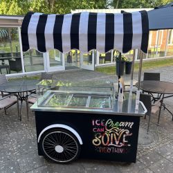 Ein mobiler Eiswagen mit schwarz-weißem Dach steht auf der Terrasse, dekoriert mit "Ice Cream Can Solve Everything".