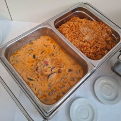 Zwei Edelstahlbehälter mit würzigem Reis und cremigem Gemüsecurry stehen auf einem Buffet bereit.