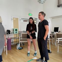 Drei Personen stehen in einem hellen Raum und unterhalten sich angeregt vor einem Flipchart.