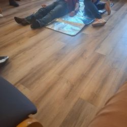 Eine Person liegt auf einer Rettungsdecke, während umstehende Menschen Erste-Hilfe-Maßnahmen leisten.