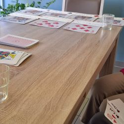Eine Gruppe spielt Karten an einem Tisch, mit Karten und Gläsern auf der Holzoberfläche.  | © Name