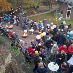 Menschen feiern im Freien mit Laternen und Feuerstellen an einem herbstlichen Nachmittag.