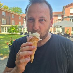 Ein Mann genießt ein Eis in einer Waffel an einem sonnigen Tag im Freien. | © Name