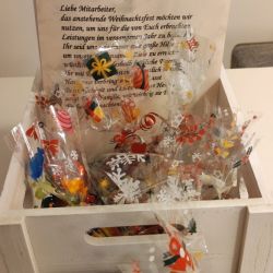 Ein festlicher Geschenkkorb voller weihnachtlicher Süßigkeiten und einer Karte mit Weihnachtsgrüßen steht auf einem Tisch.