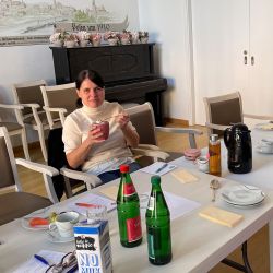 Eine Frau sitzt in einem Konferenzraum und genießt Joghurt, während Getränke und Notizen auf dem Tisch verteilt sind.