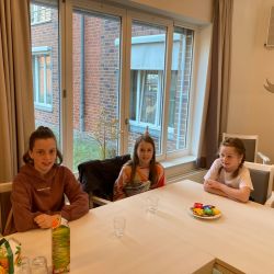 Drei Mädchen sitzen an einem Tisch in einem hellen Raum und genießen Snacks und Getränke. | © Name