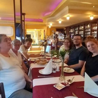 Eine Gruppe von Personen sitzt an einem liebevoll gedeckten Tisch in einem gemütlichen Restaurant und genießt die gesellige Atmosphäre.
