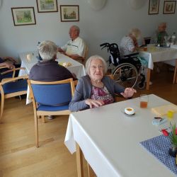 Ältere Menschen sitzen in einem gemütlichen Speisesaal und genießen gemeinsam ein Stück Kuchen.