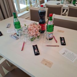 Ein dekorierter Tisch mit Getränken, Gläsern und Blumen, ideal für eine Teamveranstaltung oder Konferenzpause.