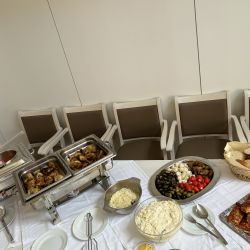 Ein reichhaltiges Buffet mit vielfältigen Speisen steht bereit, während leere Stühle im Hintergrund zum Genießen einladen.