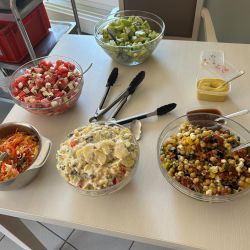 Eine Auswahl an frischen Obst- und Gemüsesalaten steht auf einem Tisch bereit zur Selbstbedienung.