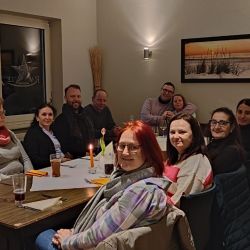 Eine Gruppe von Menschen sitzt lächelnd an einem Tisch in einem gemütlichen Restaurant und genießt den Abend.