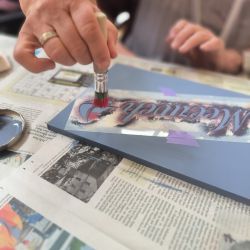 Eine Hand malt mit einem Pinsel auf einer blauen Fläche bei einem kreativen Workshop. | © Name