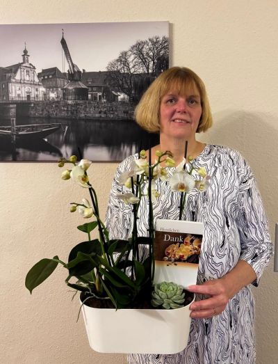 Eine Frau hält ein Blumenarrangement mit einer Dankeskarte.